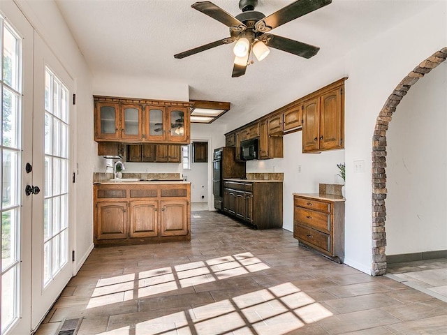 11609 Windmill Rd, Oklahoma City, OK 73162 - kitchen with brown cabinets, a ceiling fan, a sink, black appliances, and glass insert cabinets