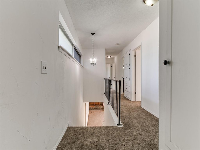 11609 Windmill Rd, Oklahoma City, OK 73162 - hallway featuring an upstairs landing, baseboards, a chandelier, a textured ceiling, and light colored carpet