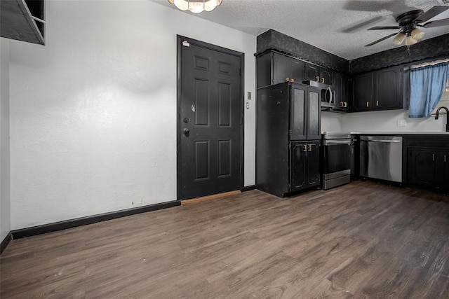 1906 NW 66th Cir, Lawton, OK 73505 - kitchen featuring a textured ceiling, dark wood finished floors, stainless steel appliances, a ceiling fan, and baseboards