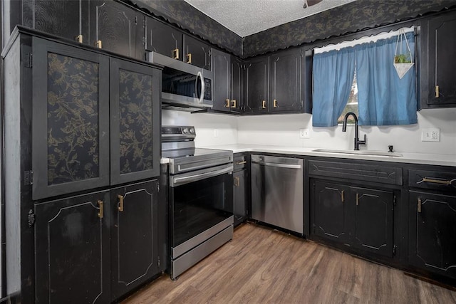 1906 NW 66th Cir, Lawton, OK 73505 - kitchen featuring a textured ceiling, wood finished floors, a sink, light countertops, and stainless steel appliances