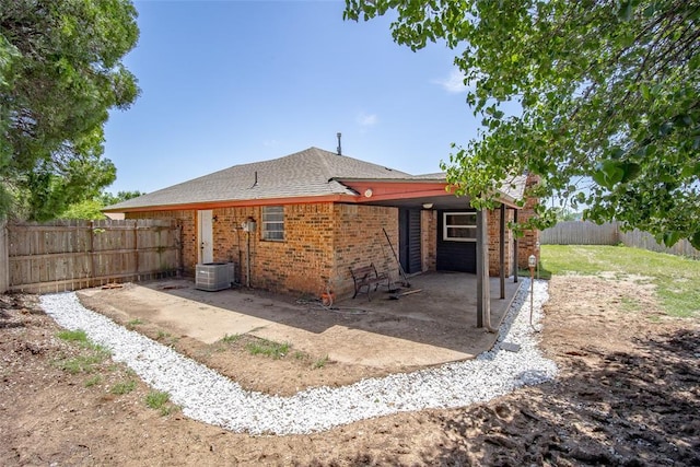 1906 NW 66th Cir, Lawton, OK 73505 - rear view of house featuring roof with shingles, brick siding, cooling unit, a fenced backyard, and a patio