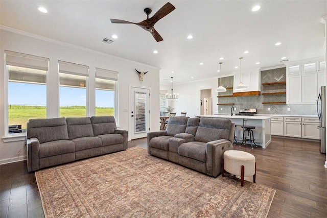 4162 Hawthorne St NW, Piedmont, OK 73078 - living room with ornamental molding, a ceiling fan, dark wood-type flooring, recessed lighting, and a chandelier