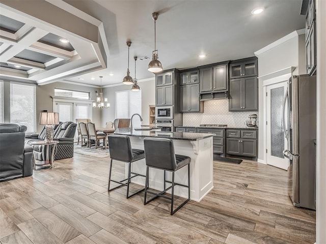 kitchen featuring tasteful backsplash, open floor plan, appliances with stainless steel finishes, a breakfast bar, and ornamental molding