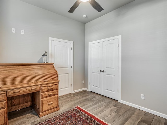 unfurnished office with baseboards, a ceiling fan, and light wood finished floors