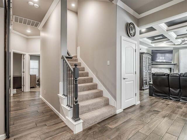 staircase featuring baseboards, wood finished floors, visible vents, and crown molding