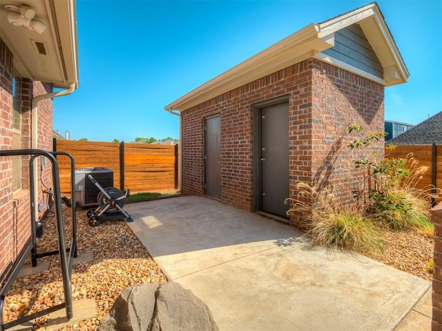 view of side of home with brick siding, a patio area, central air condition unit, and fence