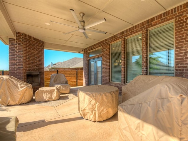 view of patio with fence, an outdoor brick fireplace, a ceiling fan, and area for grilling