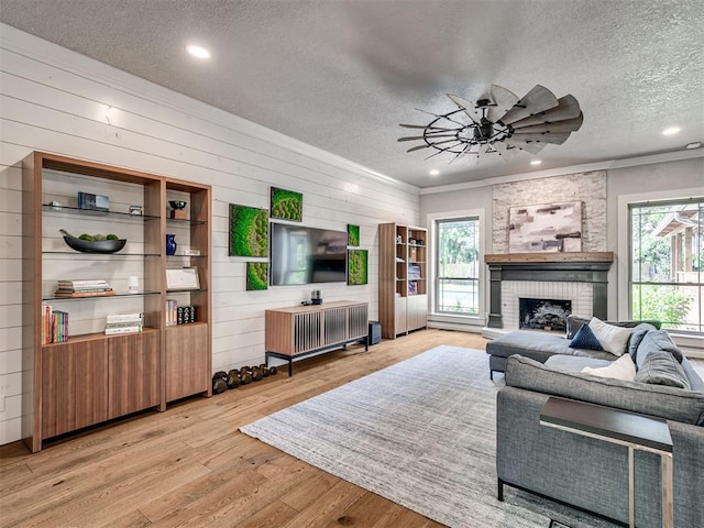 4216 Two Lakes Ave, Norman, OK 73072 - living area featuring a textured ceiling, ceiling fan, a fireplace, wooden walls, and light wood-style flooring