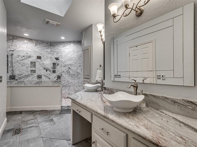 4216 Two Lakes Ave, Norman, OK 73072 - full bathroom featuring double vanity, a marble finish shower, a textured ceiling, and a chandelier