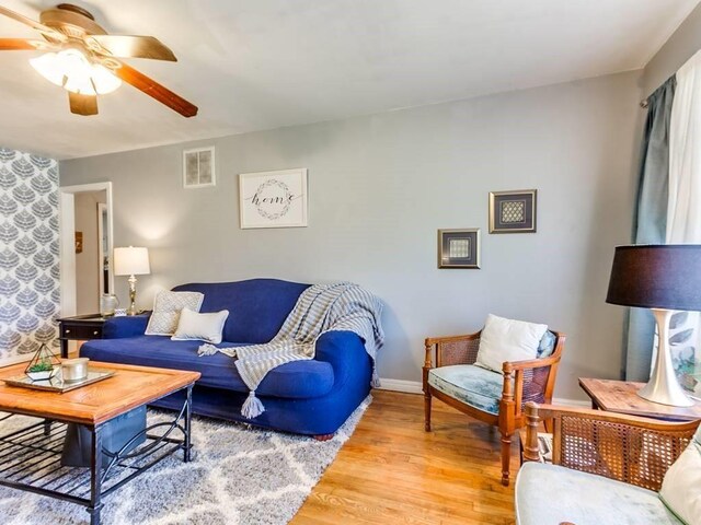living room featuring baseboards, visible vents, a ceiling fan, and light wood-style floors