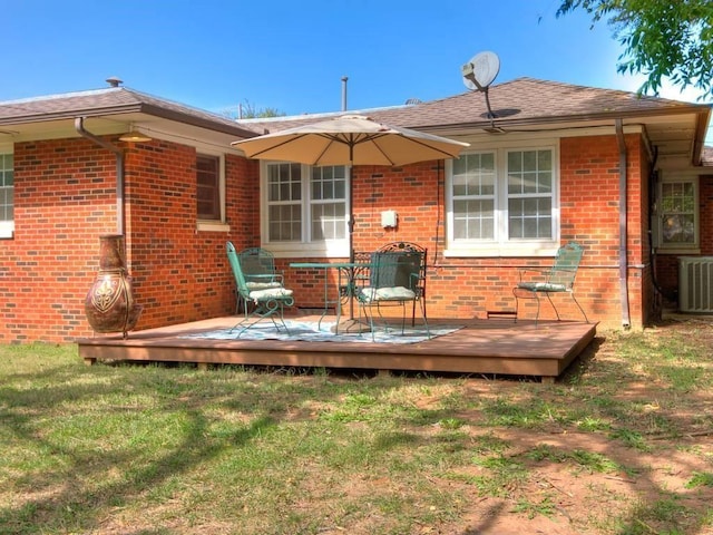 back of property with brick siding, a wooden deck, central AC unit, and a lawn