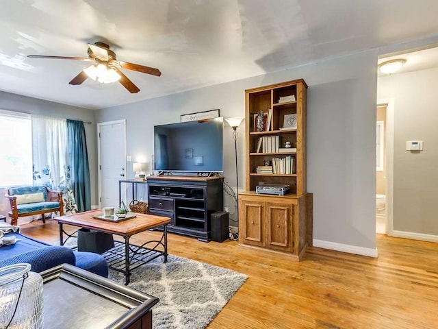 living area featuring baseboards, ceiling fan, and light wood-style flooring