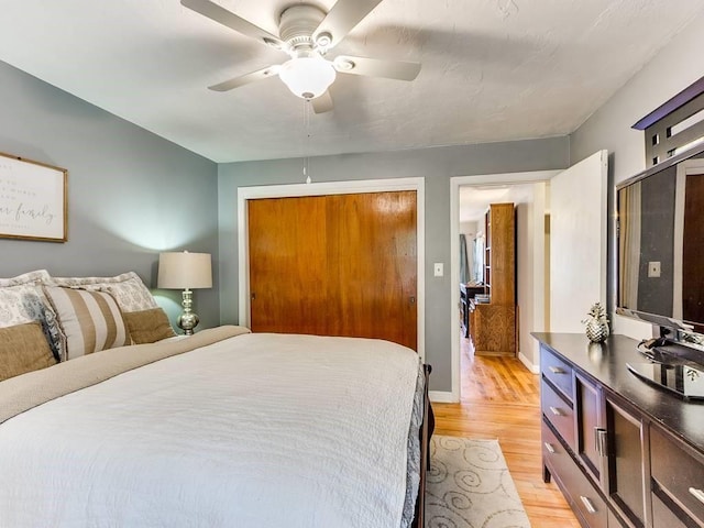 bedroom with a closet, a ceiling fan, baseboards, and light wood-style floors