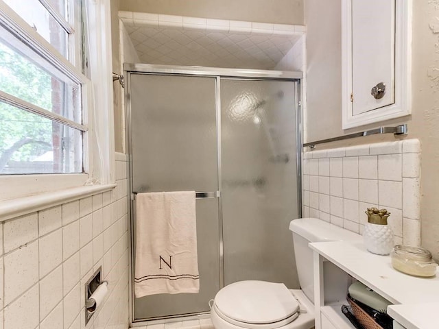 full bath featuring tile walls, a stall shower, and toilet