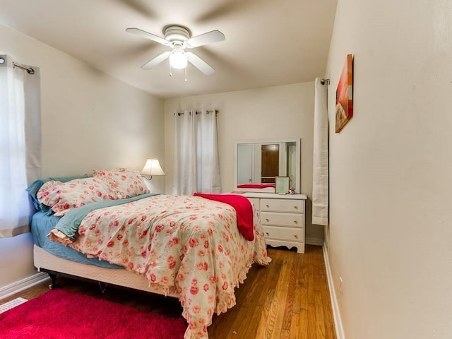bedroom featuring baseboards, visible vents, wood finished floors, and a ceiling fan