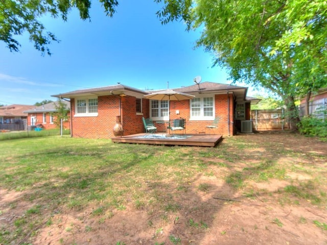 back of property featuring brick siding, a fenced backyard, central AC unit, and a lawn