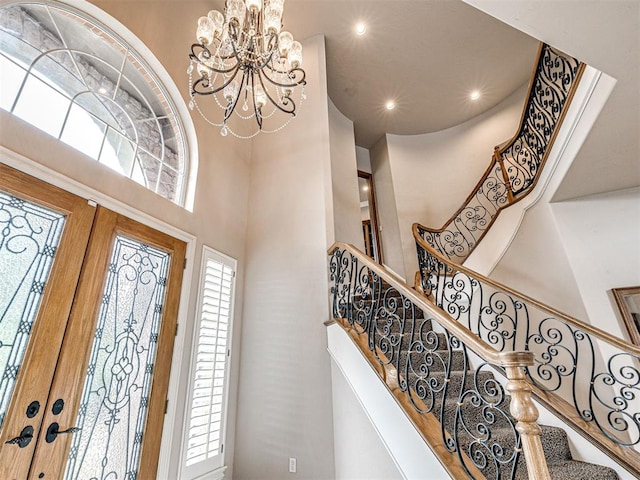 entryway featuring stairs, recessed lighting, a chandelier, and a towering ceiling