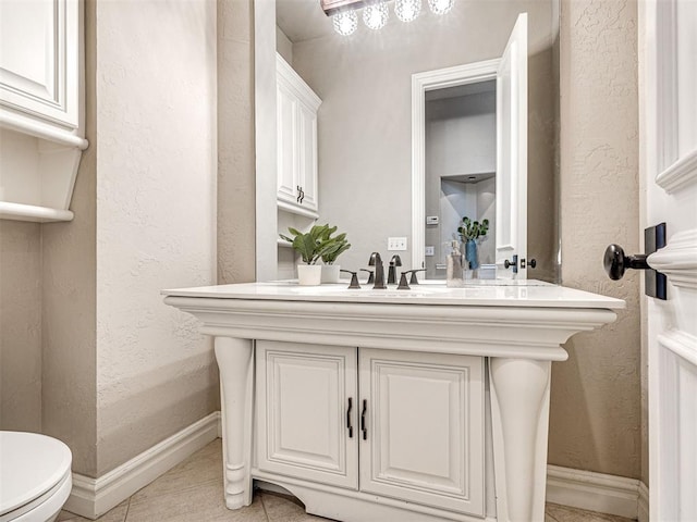 bathroom featuring tile patterned floors, a textured wall, and toilet