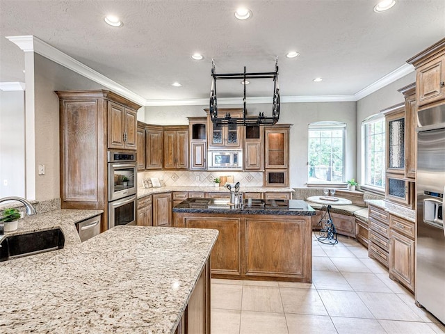 kitchen with recessed lighting, a sink, built in appliances, and light stone counters