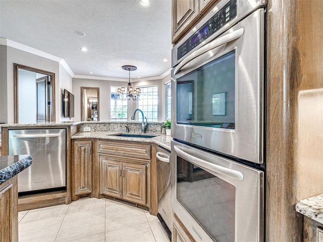 kitchen with light stone counters, a sink, a chandelier, stainless steel appliances, and ornamental molding
