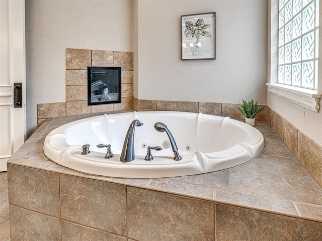 bathroom featuring a tub with jets and a fireplace