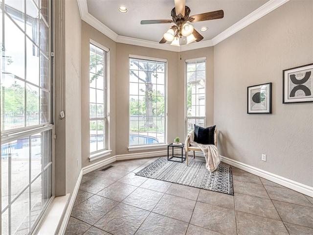 living area with baseboards, ornamental molding, a textured wall, and ceiling fan