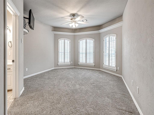 empty room featuring a textured wall, ceiling fan, a textured ceiling, carpet, and baseboards