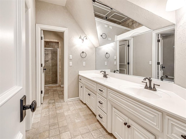 full bath with double vanity, a textured wall, a shower stall, and a sink