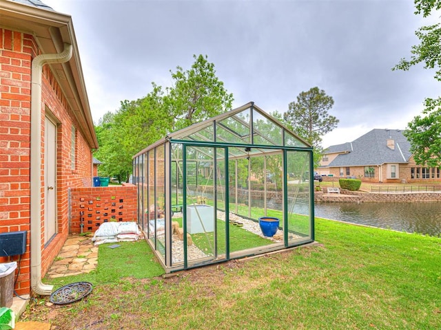view of greenhouse with a water view and a yard