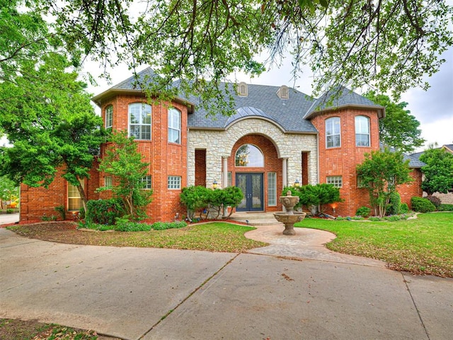 12505 Shire Ln, Oklahoma City, OK 73170 - french country home featuring french doors, a front lawn, stone siding, and brick siding