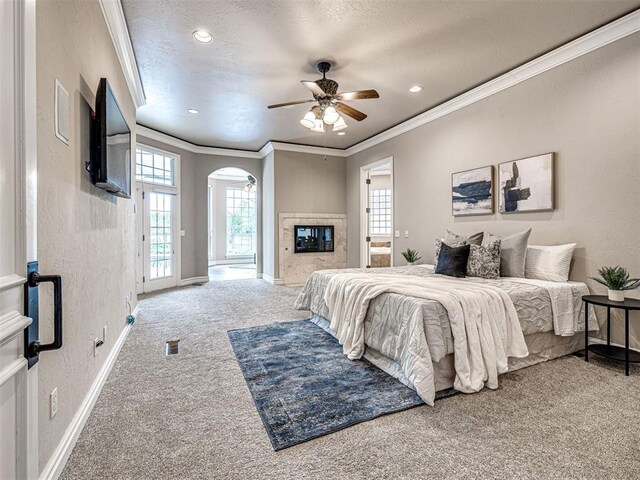 12505 Shire Ln, Oklahoma City, OK 73170 - carpeted bedroom featuring arched walkways, ornamental molding, access to exterior, recessed lighting, and a tiled fireplace