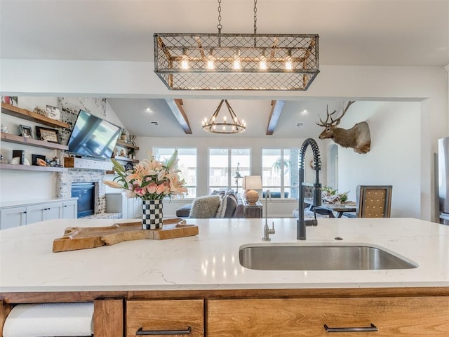 kitchen featuring open floor plan, light stone counters, a sink, and plenty of natural light