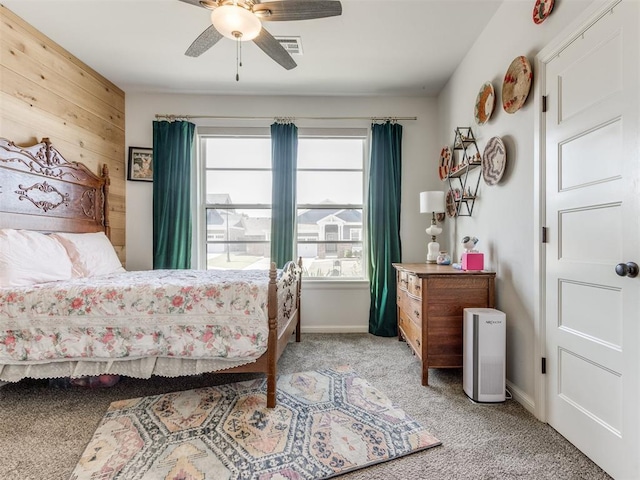 bedroom featuring wooden walls, visible vents, light carpet, baseboards, and ceiling fan