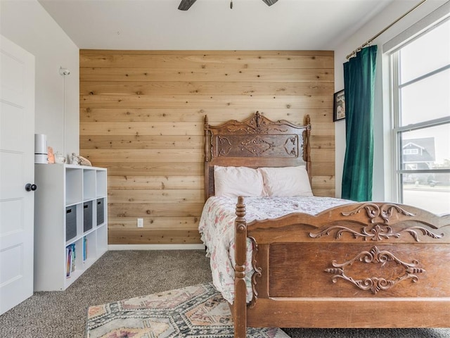 carpeted bedroom featuring wood walls and ceiling fan