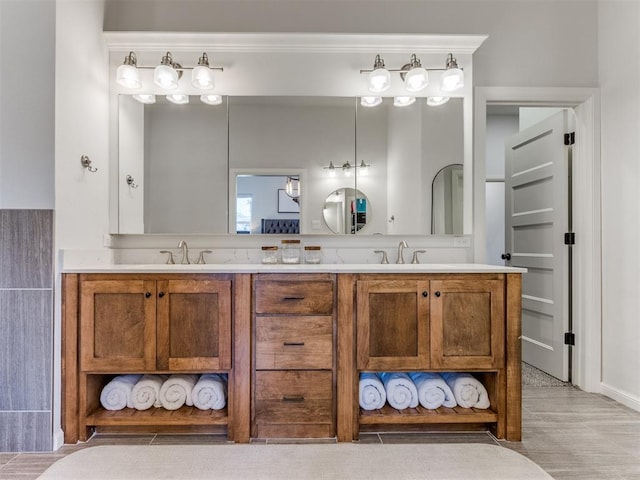 bathroom with wood finished floors, a sink, double vanity, and crown molding