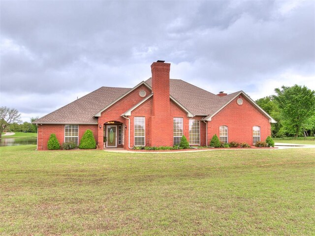 single story home with roof with shingles, a chimney, a front lawn, and brick siding
