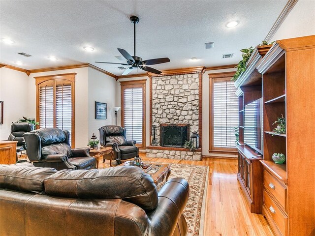 living room featuring a textured ceiling, ornamental molding, ceiling fan, and light wood-style floors