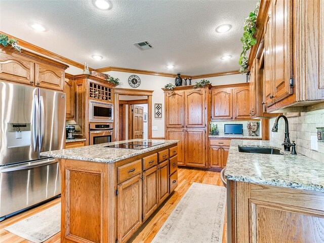 kitchen featuring a sink, a textured ceiling, a kitchen island, and stainless steel appliances