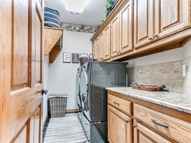 clothes washing area featuring independent washer and dryer, light tile patterned flooring, and cabinet space