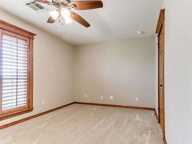 empty room with a ceiling fan, a textured ceiling, visible vents, baseboards, and light carpet
