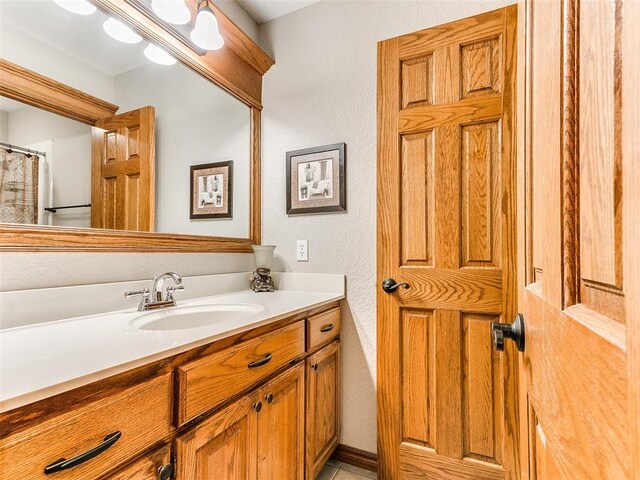 full bath featuring vanity and a textured wall