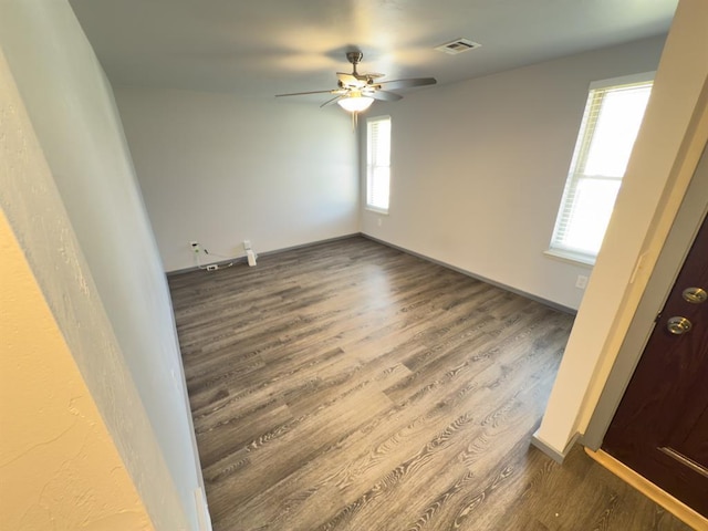 unfurnished room featuring ceiling fan, wood finished floors, visible vents, and plenty of natural light