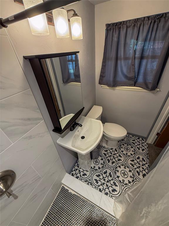 half bath with tile patterned flooring, toilet, and a sink