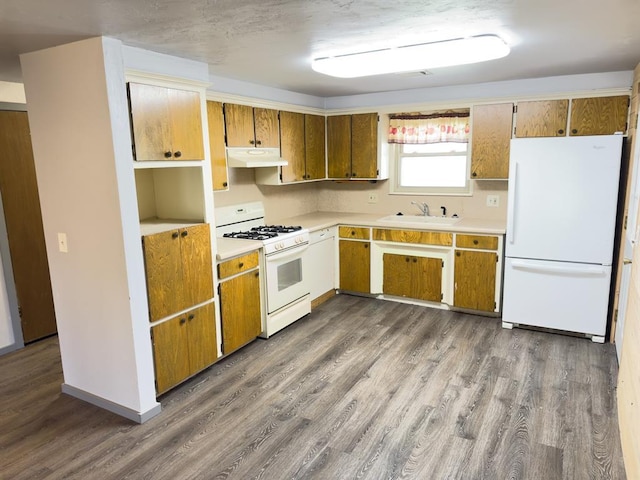 kitchen with dark wood-style floors, under cabinet range hood, a sink, and white appliances
