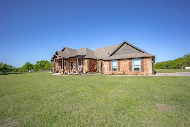 craftsman inspired home featuring fence, roof with shingles, a front lawn, and brick siding