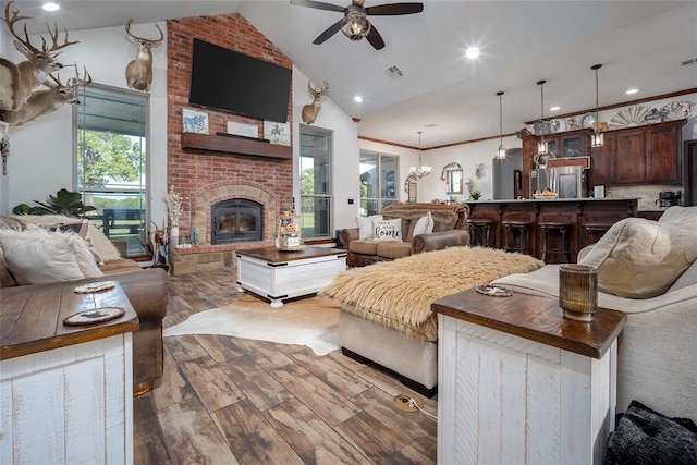 living room with ceiling fan with notable chandelier, wood finished floors, a wealth of natural light, and lofted ceiling