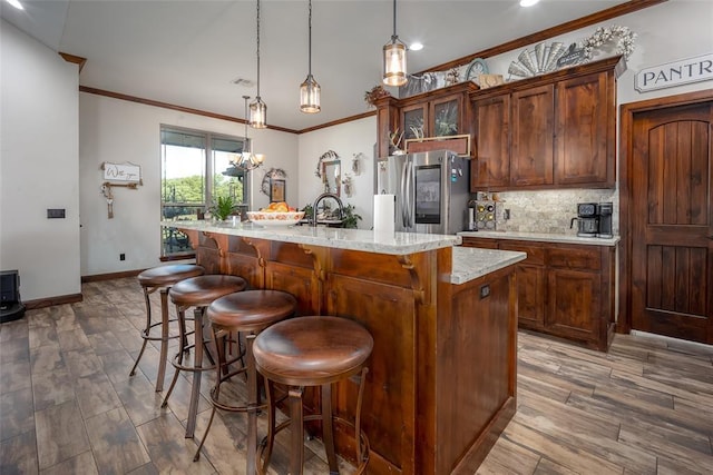 kitchen featuring crown molding, a breakfast bar, an island with sink, smart refrigerator, and tasteful backsplash