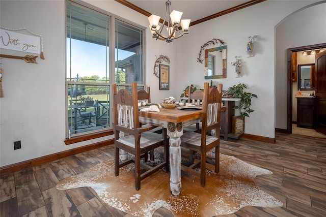 dining room with crown molding, an inviting chandelier, hardwood / wood-style floors, baseboards, and arched walkways