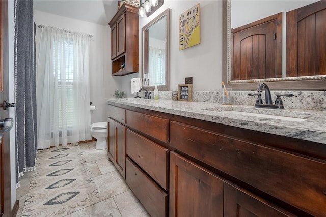 bathroom with a sink, toilet, and double vanity