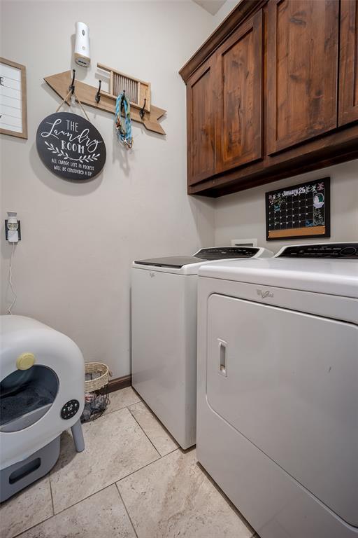 washroom featuring washing machine and clothes dryer, baseboards, light tile patterned floors, and cabinet space